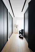 Elegant dressing area with floor-to-ceiling, black fitted wardrobes; tailors' dummies and black armchair in background