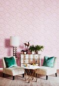 Upholstered chairs and table in front of chest of drawers against pink wallpaper