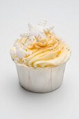 A cupcake decorated with yellow icing, silver balls and snowflakes