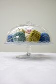 Balls of wool of various colours under glass cover
