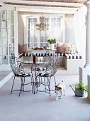 Pretty wire chairs and table with glass top on romantic country-house terrace