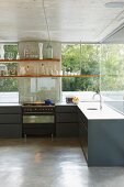 Anthracite, purist kitchen counter below suspended shelves in front of glass facade