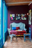 Seating area with antique sofa, side table & chairs next to blue terrace doors