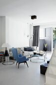 Fifty Lesesessel mit blauem Bezug vor runden Couchtischen und gemütliches Polstersofa im Wohnzimmer