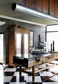 Steampunk kitchen with spotlights in air duct pipe above island counter made from old workbench with glass top