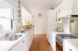 Long, narrow modern kitchen with white units & breakfast bar
