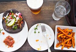 Tacos with jackfruit, lettuce, radishes, coriander and lime, served with sweet potato chips and beer