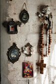 Miniature pictures of flowers and rustic rosary on roughly plastered wall