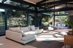 Pale chaise sofa and Bauhaus-style dining area in contemporary glass and steel house