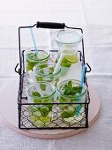 Several glasses of lemon juice with mint in a wire basket
