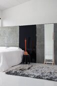 Minimalist gallery bedroom with grey flokati rug and large, full-length mirror against grey partition