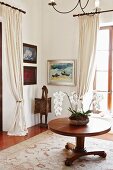 Orchideenschale auf rundem Holztisch; Malerei und Kunstobjekt in Zimmerecke