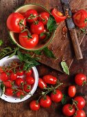 Verschiedene reife Tomaten in Schüsseln und auf Holzbrett