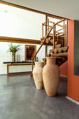 Wohnraum mit Innentreppe aus Holz und Bodenvasen