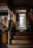 Ehemalige Scheune dient als Diele - Tiertrophäe an Holzwand, daneben Holztreppe vor offener Tür