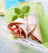 Wraps with ham, tomatoes and mozzarella, in a Tupperware container