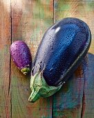 Two aubergines (large and small) on a wooden surface
