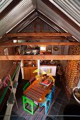 Blick von oben auf Essplatz mit farbigen Stühlen und Einblick in Dachstuhl mit Metallabdeckung