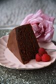 A slice of chocolate cake with raspberries and a rose for Valentine's Day
