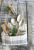 Silver spoons and wooden clothes pins in a pocket made from a linen dish towel