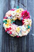 Decorative wreath of multicoloured flowers on wooden wall