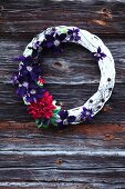 Decorative wreath with clematis flowers and dahlias on wooden wall