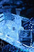 Still-life arrangement of jewellery boxes, perfume bottles and vase on silver tray in bluish light