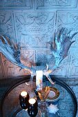 Tealights and silvered stag's antlers on tray in front of tiled wall with antique embossed motifs
