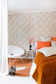 Easter atmosphere in bedroom with orange accents combined with hen-patterned wallpaper, rabbit soft toy and Easter bouquet