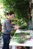 Floristin beim Binden eines Blumenstrausses an Tisch in Bauerngarten