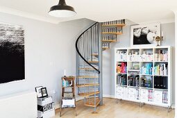 Wohnzimmerecke mit Bücherregal und Wendeltreppe zum Mezzanin in englischem Fabrikloft