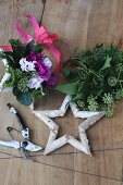 Hand-crafted birch bark stars decorated with cyclamen and leaves and secateurs on wooden surface