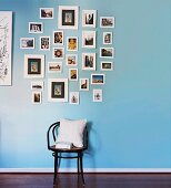 Thonet chair with white cushions below collection of pictures on blue wall