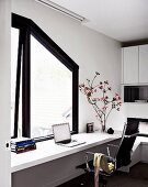 weiße durchgehende Schreibplatte vor dunkel gerahmtem Fenster mit Dachschrägung, ergänzt mit Eames Stuhl