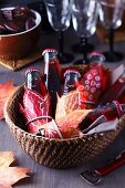 Basket of small bottles of drink decorated with painted autumn leaves