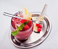 Fruit cocktail with raspberries, lemon and mint, on a silver tray