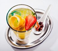 Fruit cocktail with lemon juice, lemon peel and strawberries on a silver tray