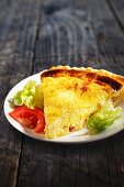 A slice of cheese quiche with salad garnish