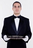 Portrait of male waiter holding tray