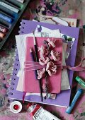Artistic collection of pictures, notebook, paintbrushes and crocheted flowers tied in bundle with pink velvet ribbon