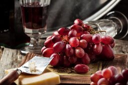 Rote Trauben, Käse und Rotwein auf altem Holztisch