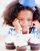 Träumendes Mädchen mit Geburtstags-Cupcakes