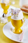 Butterfly shapes punched from old maps decorating boiled egg on breakfast table