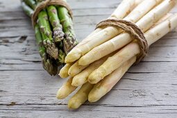 Grüner und weisser Spargel, gebündelt, auf Holzuntergrund