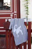 Grey T-shirt with hand-sewn animal motif hanging over wooden fence