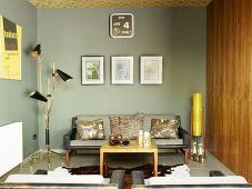 Loungeecke mit grau getönten Wänden in modernem Retrolook mit kleinem Couchtisch, Tierfellteppich & Sofa zwischen Stehleuchten im Fiftiesstil