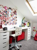 Fabric pin board above teenager's desk in bright attic bedroom