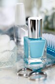 Blaue Nagellackflasche mit Nagelschere und Beauty-Utensilien
