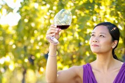 Frau mit einem Glas Burgunder-Rotwein im Weinberg