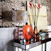 Ornaments on mirrored console table against floral wallpaper